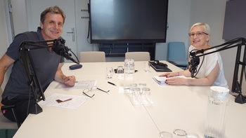 Bernd Stampfl und Angelika Ludwig sitzen an einem Tisch mit Microphonen und lächeln in die Kamera.